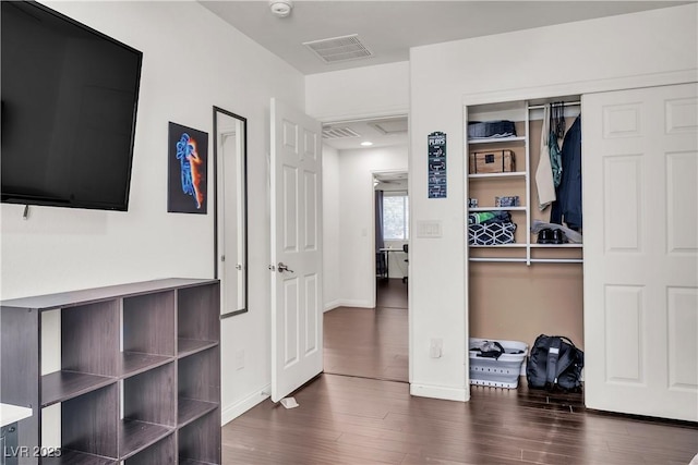 bedroom featuring dark wood-style flooring, visible vents, baseboards, and a closet