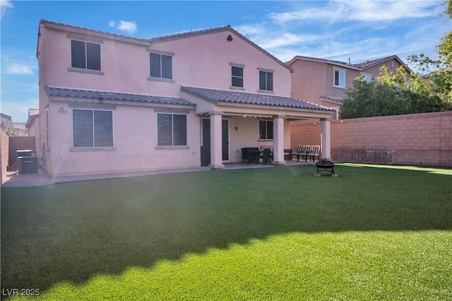 back of property with a yard, a tiled roof, fence, a patio, and stucco siding