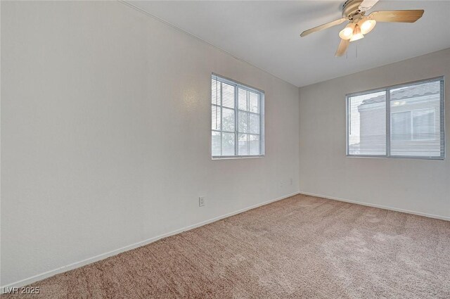 carpeted spare room featuring baseboards and a ceiling fan