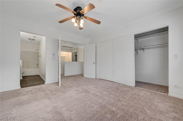 unfurnished bedroom featuring ensuite bath, a closet, a ceiling fan, and carpet