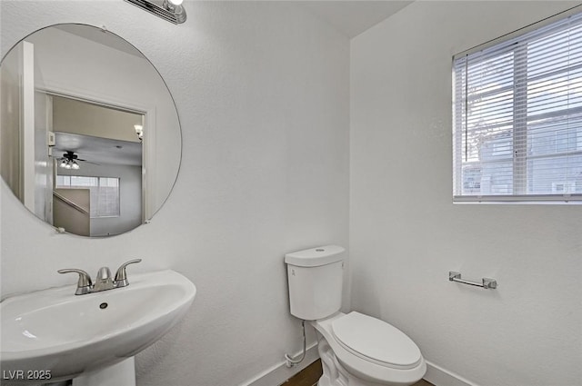 half bath featuring toilet, a sink, and baseboards