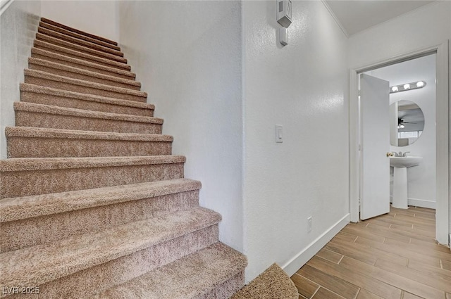 staircase with crown molding, baseboards, and wood tiled floor