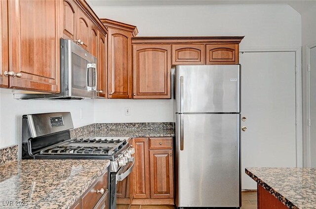 kitchen featuring brown cabinetry, stone counters, and stainless steel appliances