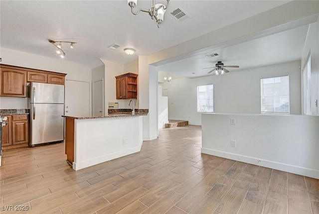 kitchen featuring open floor plan, freestanding refrigerator, open shelves, visible vents, and dark stone counters