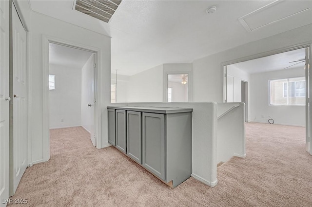 corridor with visible vents, an upstairs landing, and light carpet