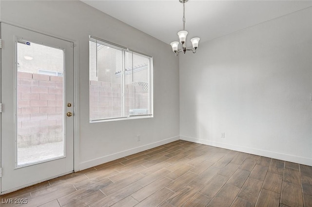 spare room with a notable chandelier, baseboards, and wood tiled floor
