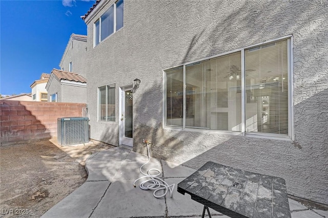 rear view of house with cooling unit, stucco siding, a patio, fence, and a tile roof