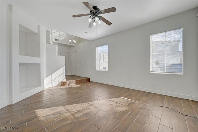 interior space with ceiling fan with notable chandelier, visible vents, baseboards, and wood finish floors