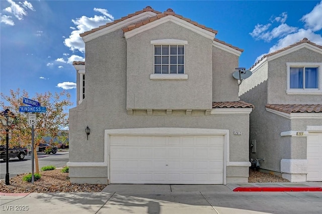 view of front of property featuring driveway, stucco siding, a tiled roof, and an attached garage