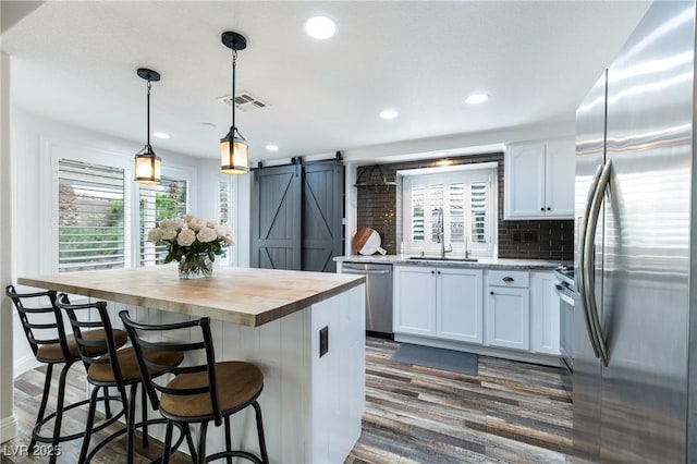 2401 Rice Flower Cir, Las Vegas, NV 89134 - kitchen with appliances with stainless steel finishes, a barn door, a sink, wooden counters, and dark wood-style flooring