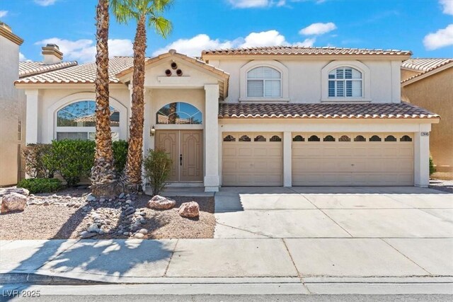 2445 Antler Point Dr, Henderson, NV 89074 - mediterranean / spanish home with concrete driveway, stucco siding, a garage, a chimney, and a tiled roof