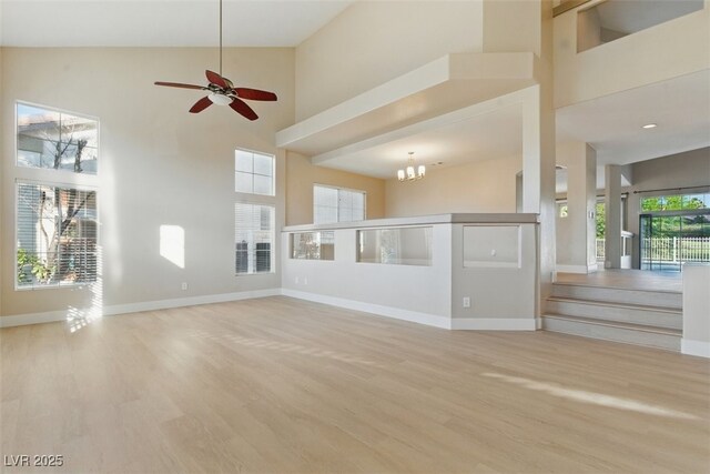 2445 Antler Point Dr, Henderson, NV 89074 - unfurnished living room featuring high vaulted ceiling, wood finished floors, a ceiling fan, and a chandelier