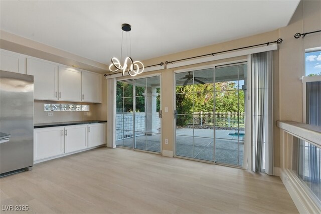 2445 Antler Point Dr, Henderson, NV 89074 - kitchen with stainless steel fridge, light wood-type flooring, white cabinets, and a chandelier