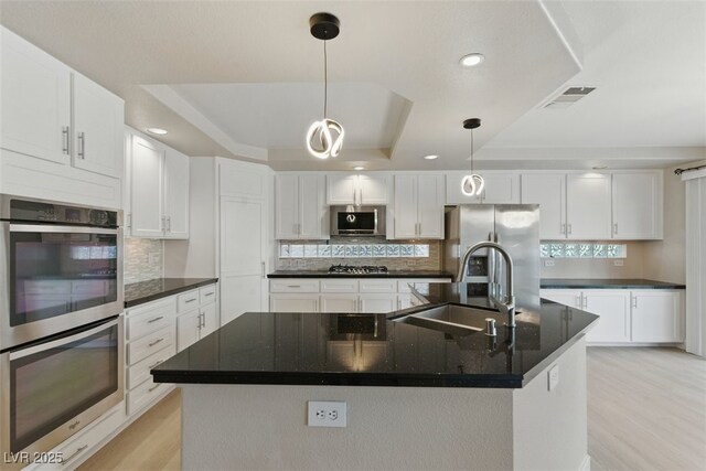 2445 Antler Point Dr, Henderson, NV 89074 - kitchen featuring appliances with stainless steel finishes, a raised ceiling, light wood-type flooring, backsplash, and white cabinetry