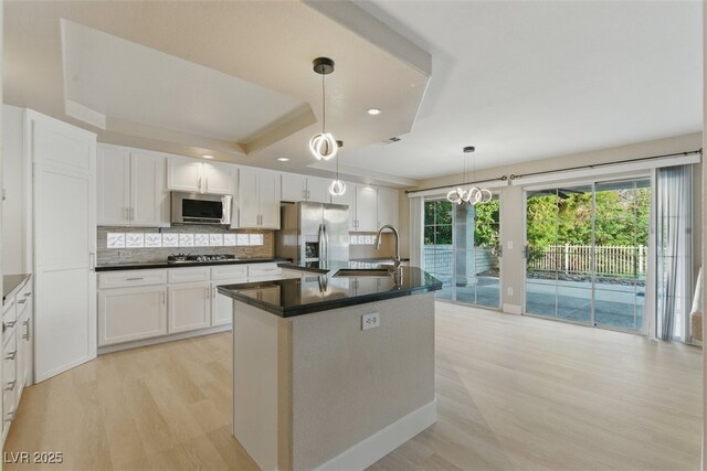 2445 Antler Point Dr, Henderson, NV 89074 - kitchen featuring stainless steel appliances, light wood finished floors, a raised ceiling, dark countertops, and white cabinets