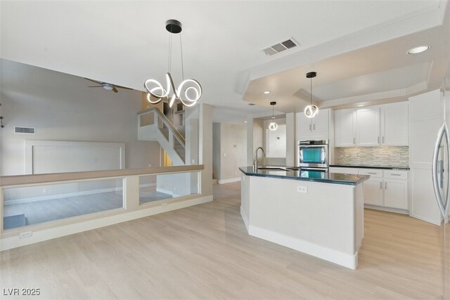 2445 Antler Point Dr, Henderson, NV 89074 - kitchen featuring a raised ceiling, dark countertops, light wood-type flooring, white cabinets, and recessed lighting