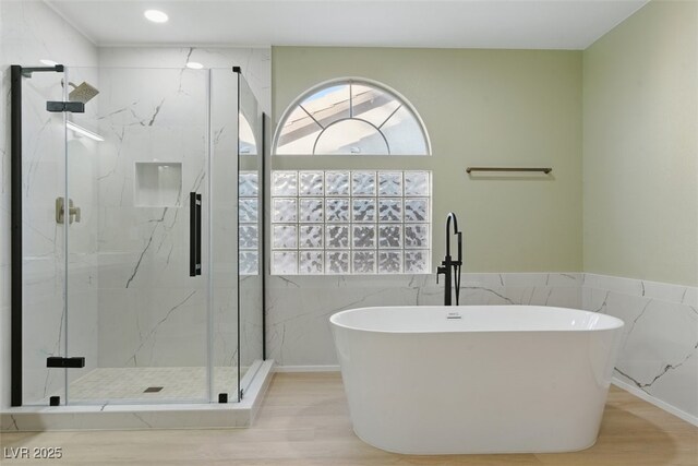 2445 Antler Point Dr, Henderson, NV 89074 - bathroom with a freestanding tub, tile walls, a marble finish shower, wood finished floors, and wainscoting