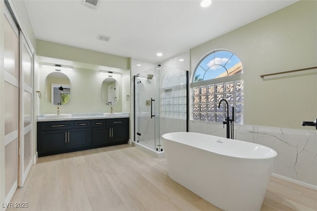 2445 Antler Point Dr, Henderson, NV 89074 - full bathroom featuring a shower stall, double vanity, a freestanding bath, wood finished floors, and recessed lighting