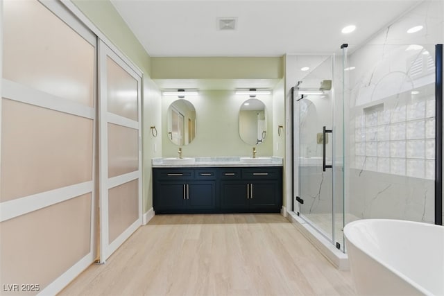 2445 Antler Point Dr, Henderson, NV 89074 - bathroom featuring a soaking tub, a marble finish shower, double vanity, and wood finished floors