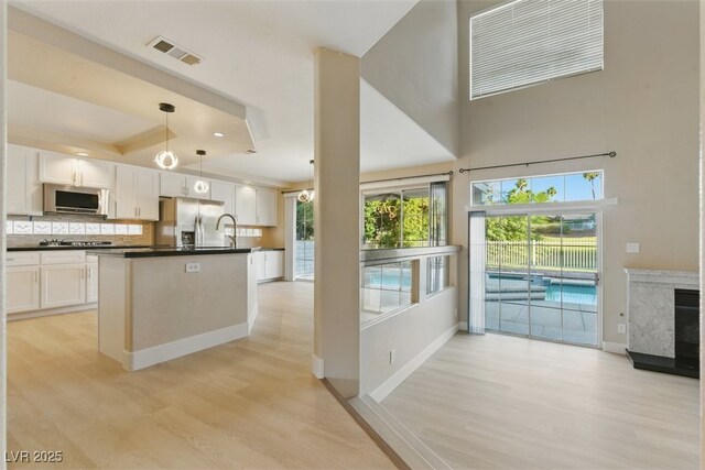 2445 Antler Point Dr, Henderson, NV 89074 - kitchen featuring stainless steel appliances, dark countertops, light wood finished floors, decorative backsplash, and a towering ceiling