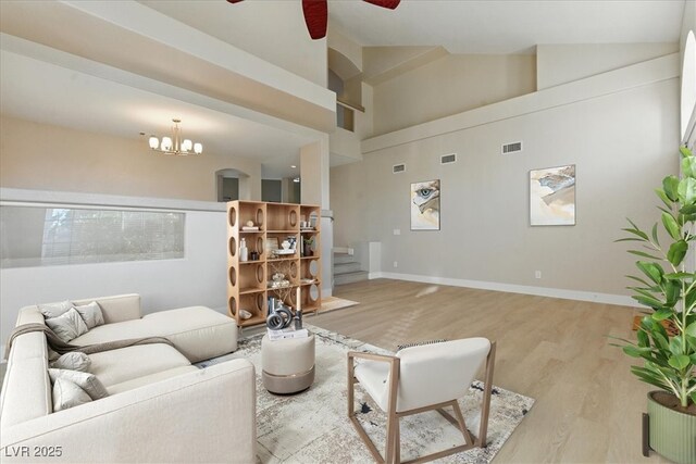2445 Antler Point Dr, Henderson, NV 89074 - living room featuring light wood finished floors, ceiling fan, stairs, a chandelier, and high vaulted ceiling