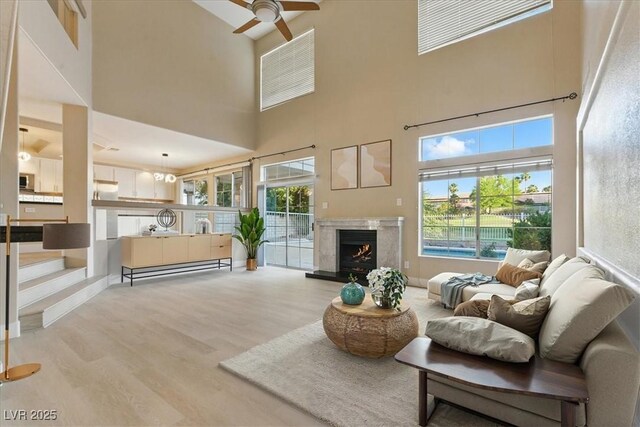 2445 Antler Point Dr, Henderson, NV 89074 - living area featuring light wood-style floors, a high ceiling, ceiling fan, and a premium fireplace