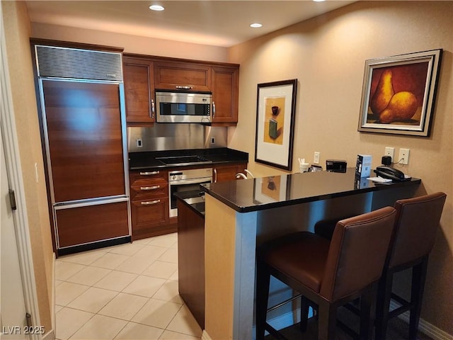 135 E Harmon Ave Unit 3320, Las Vegas, NV 89109 - kitchen featuring stainless steel appliances, a peninsula, dark countertops, a kitchen bar, and recessed lighting
