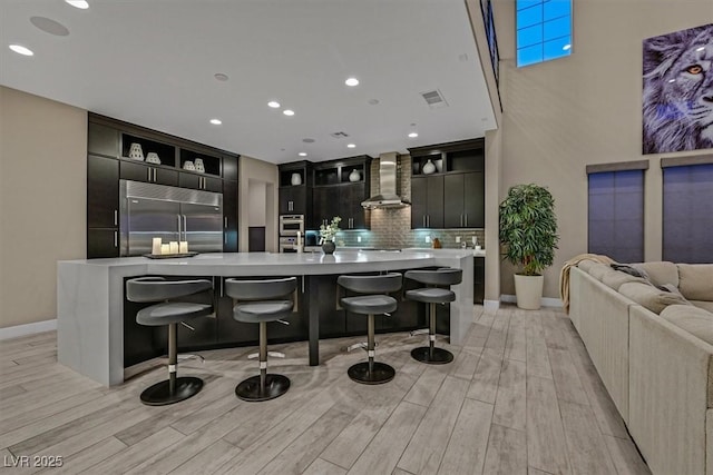10 Olympia Outlook Dr, Las Vegas, NV 89141 - kitchen with decorative backsplash, stainless steel appliances, light countertops, dark cabinetry, and wall chimney exhaust hood