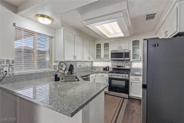 10103 Flagstaff Butte Ave, Las Vegas, NV 89148 - kitchen with visible vents, white cabinets, glass insert cabinets, a peninsula, and stainless steel appliances