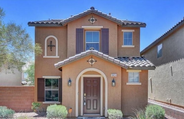 view of front of property featuring a tiled roof, fence, and stucco siding