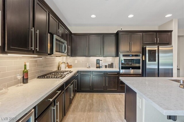 1225 Olivia Pkwy, Henderson, NV 89011 - kitchen with light wood-style floors, dark brown cabinetry, tasteful backsplash, recessed lighting, and appliances with stainless steel finishes