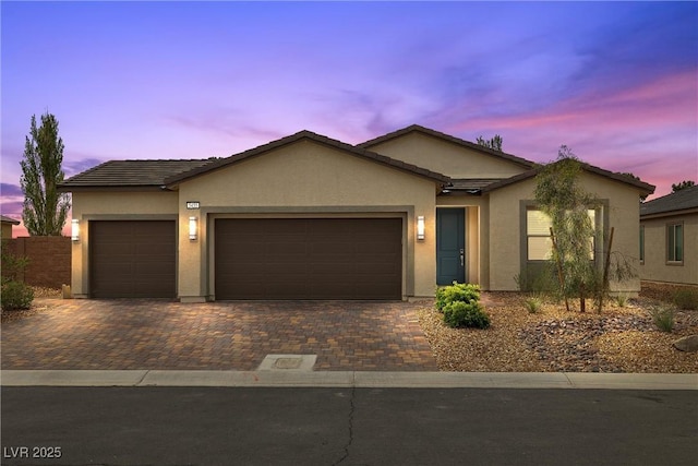 5455 Eleganza Ave, Pahrump, NV 89061 - ranch-style house with stucco siding, a tiled roof, decorative driveway, and an attached garage