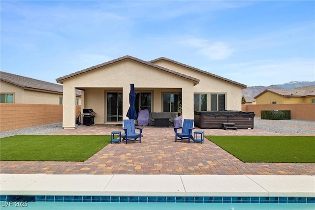5455 Eleganza Ave, Pahrump, NV 89061 - rear view of property with stucco siding, a patio area, a fenced backyard, a hot tub, and a yard