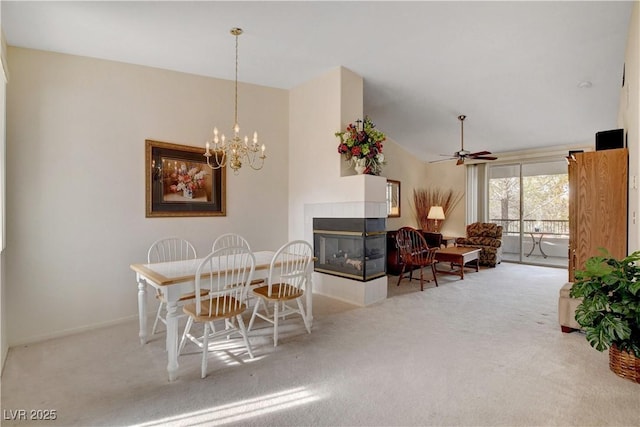 dining space featuring a tile fireplace, carpet flooring, and ceiling fan with notable chandelier