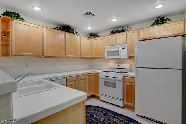 kitchen with visible vents, tile counters, white appliances, and light brown cabinets