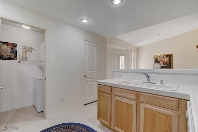 kitchen featuring light brown cabinets, a sink, a notable chandelier, and hanging light fixtures
