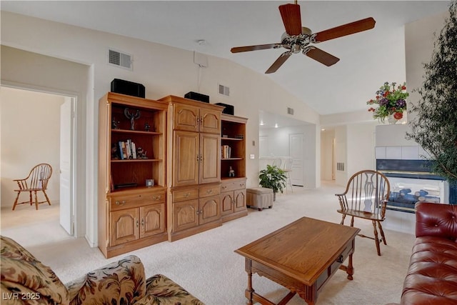living area featuring high vaulted ceiling, visible vents, light colored carpet, and a ceiling fan