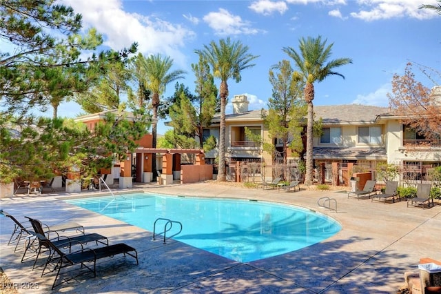pool with a patio area and fence