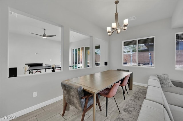 dining room featuring wood tiled floor, ceiling fan with notable chandelier, baseboards, and visible vents