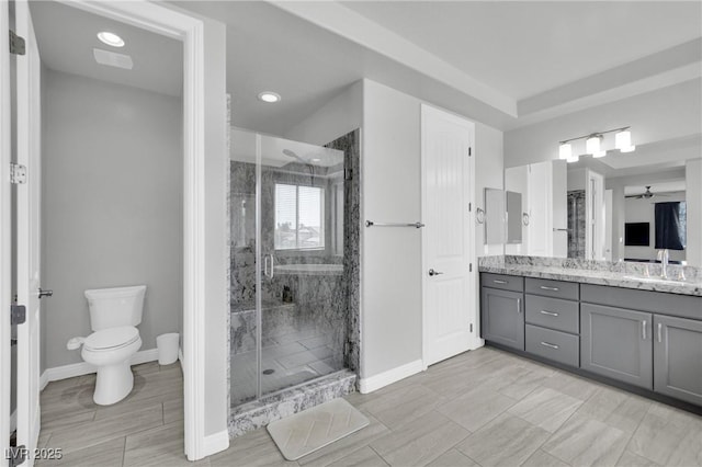 full bath with toilet, a shower stall, vanity, and baseboards