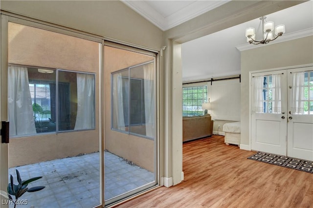 foyer entrance with a chandelier, french doors, ornamental molding, and wood finished floors