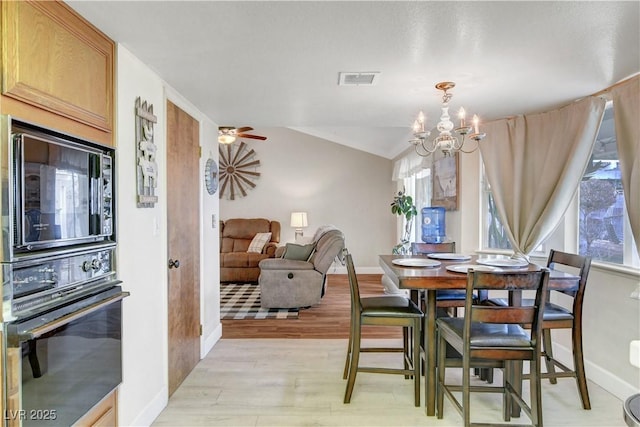 dining space featuring baseboards, vaulted ceiling, visible vents, light wood finished floors, and ceiling fan with notable chandelier