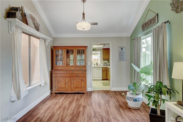 foyer entrance with light wood-style flooring, baseboards, ornamental molding, and visible vents