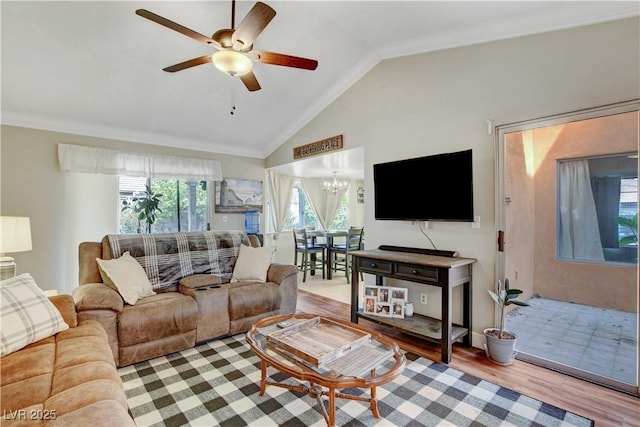 living room featuring ceiling fan with notable chandelier, wood finished floors, ornamental molding, and lofted ceiling