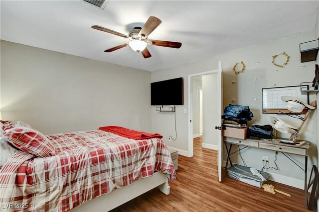 bedroom featuring visible vents, baseboards, a ceiling fan, and wood finished floors