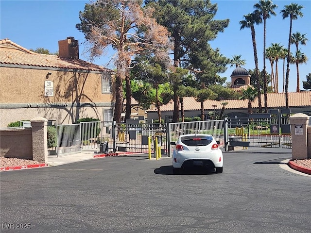 view of street featuring a gate, a gated entry, and curbs