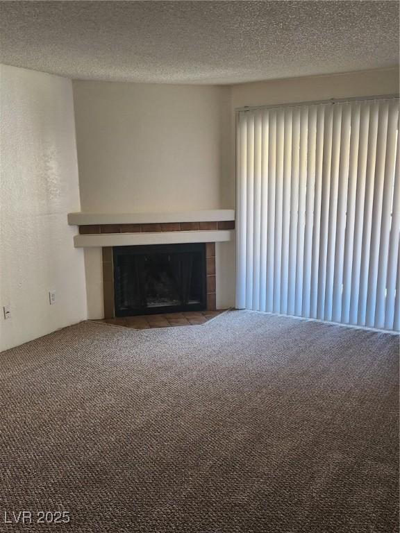 unfurnished living room featuring a textured ceiling, carpet, radiator heating unit, and a tile fireplace