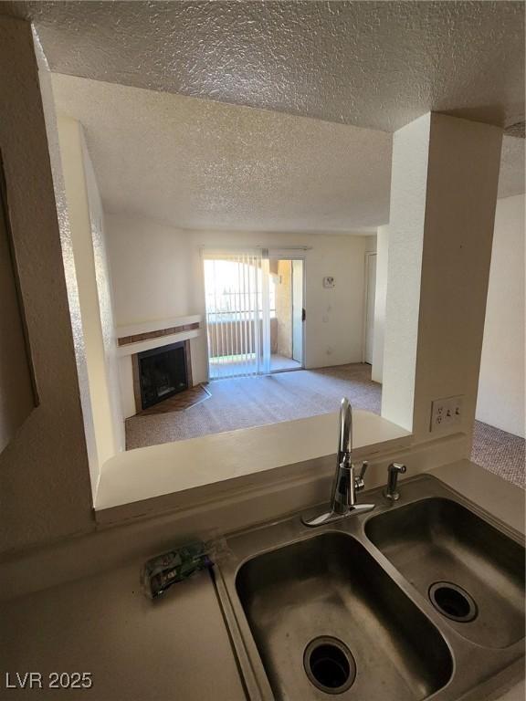 kitchen with a sink, a fireplace with flush hearth, and a textured ceiling