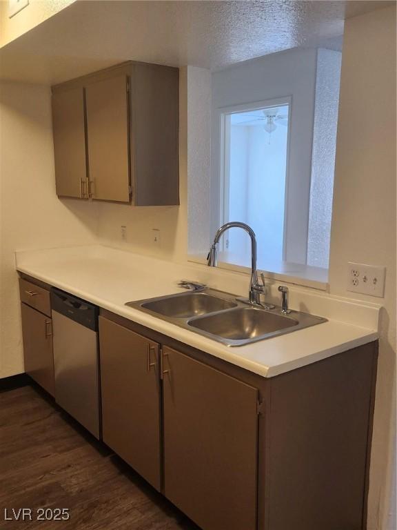 kitchen featuring light countertops, dark wood-type flooring, a sink, and dishwasher