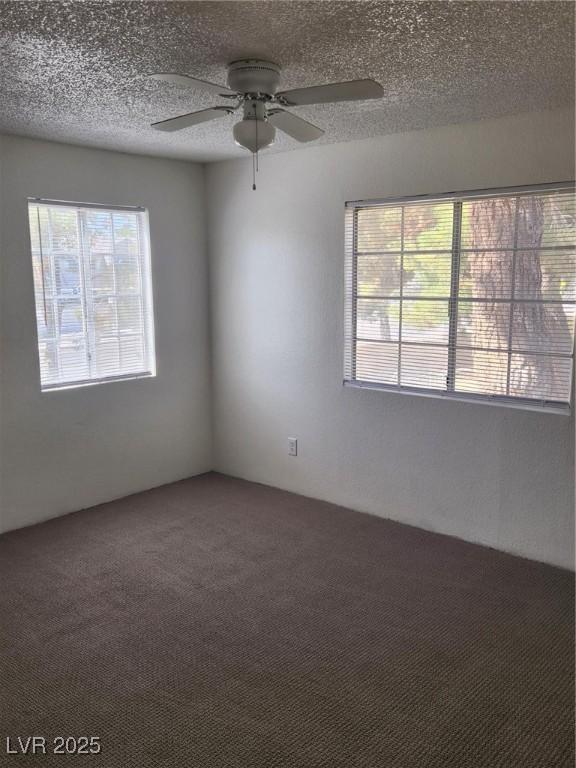 carpeted spare room with ceiling fan and a textured ceiling